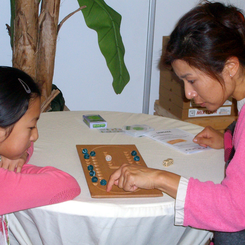 Mutter und Tochter studieren gemeinsam das Samsara-Spielbrett